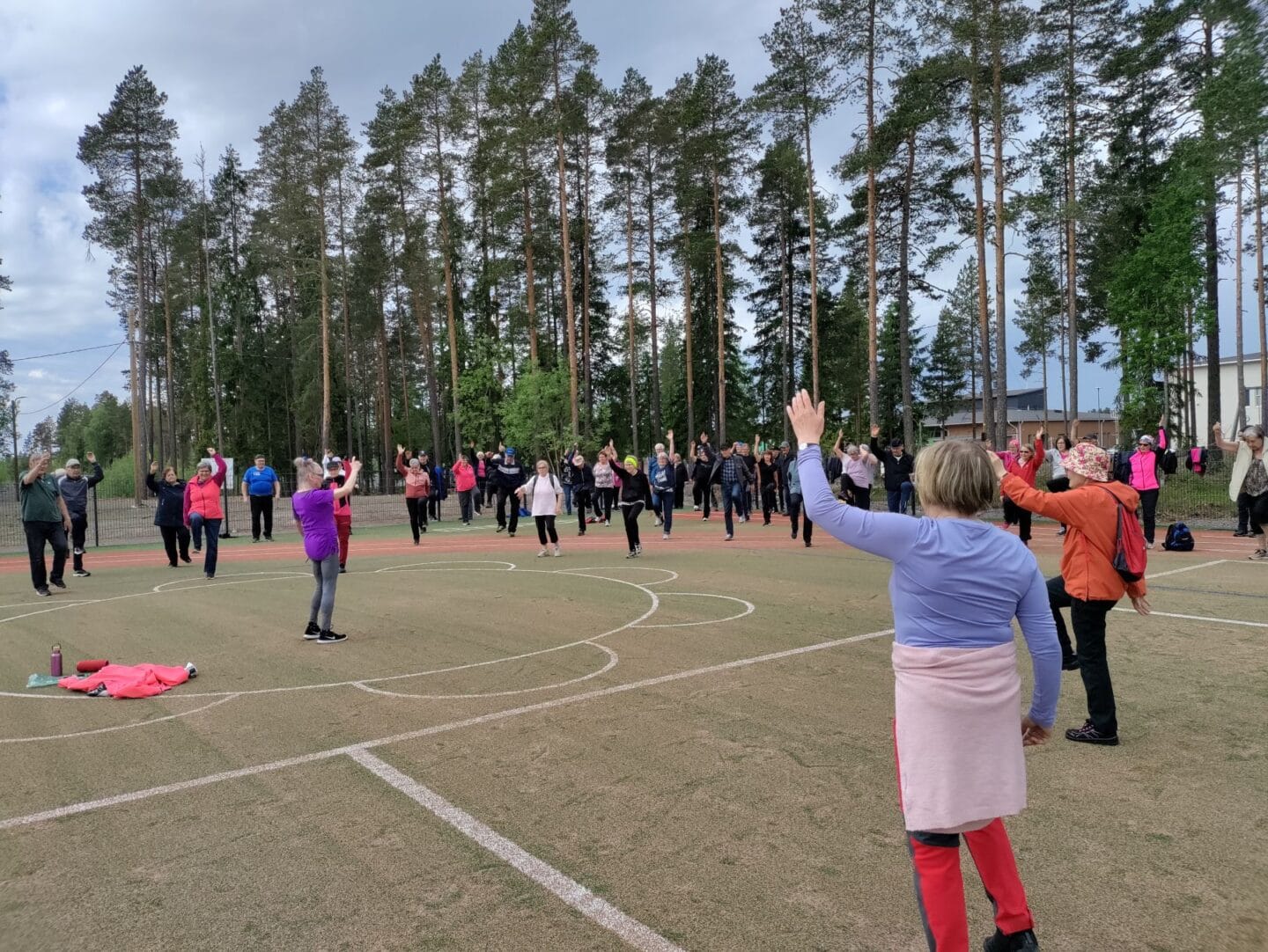 Ryhmä senioreita jumppaa urheilukentällä