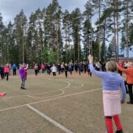 Ryhmä senioreita jumppaa urheilukentällä